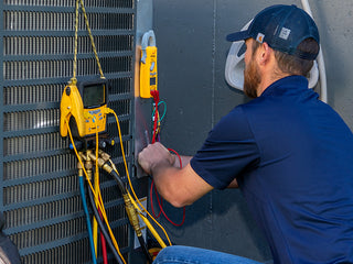 Service tech working outside on a unit - part of the Comfort Guard Advantage Plan Preventative Maintenance with Donaldson Heating & Air Conditioning.